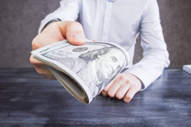 bigstock-Businessman-Handing-Money-124174637